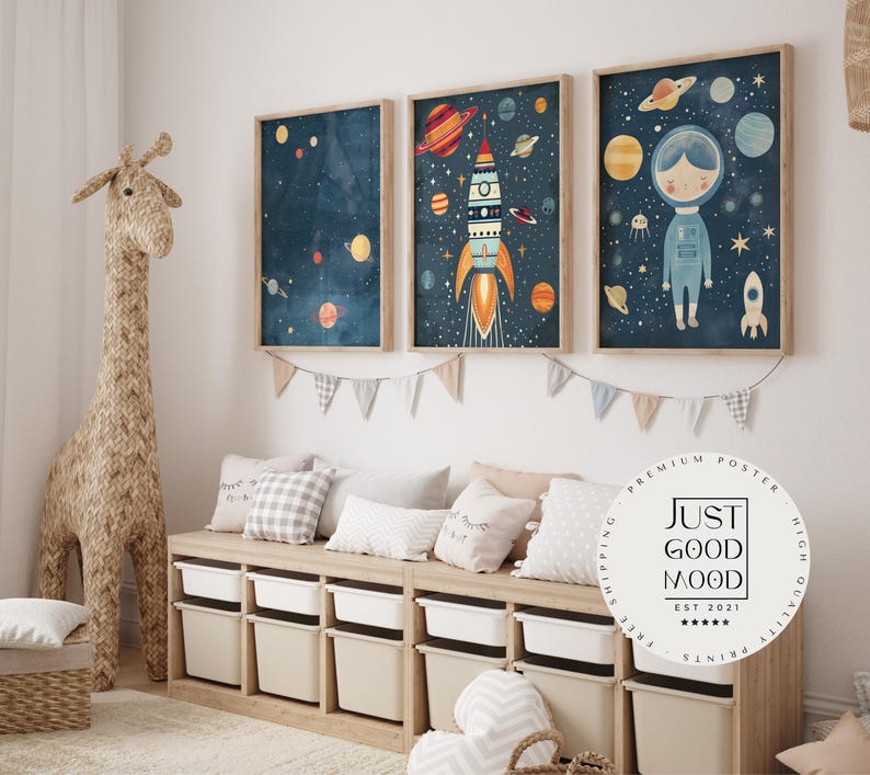 May include: Three framed illustrations of a rocket ship, planets, and an astronaut in space. The illustrations are on a white wall above a wooden bench with white storage bins. The bench is decorated with cushions.