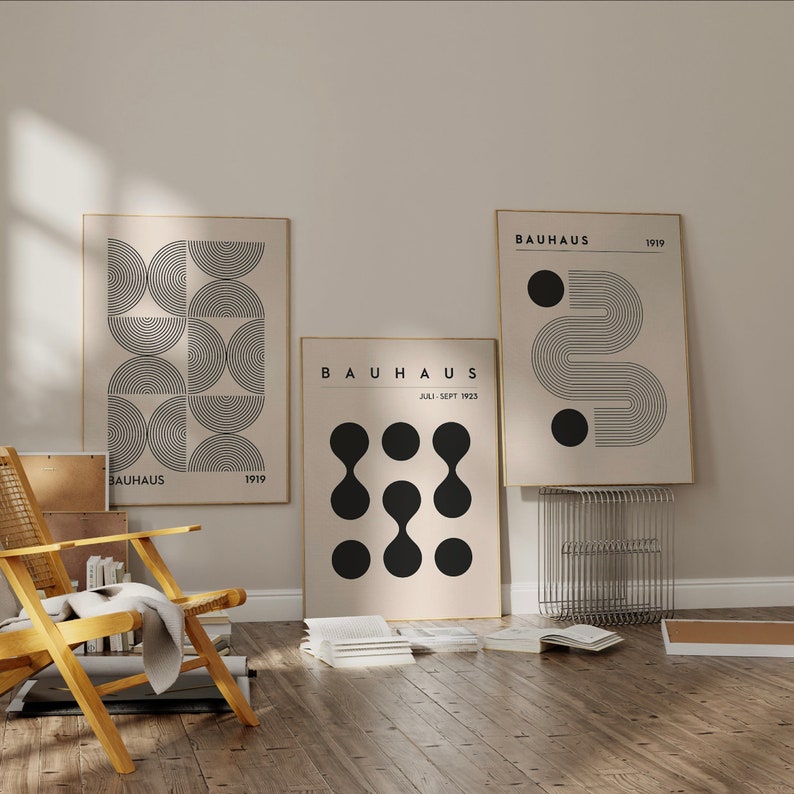 Puede incluir: Tres impresiones enmarcadas con dise&ntilde;os geom&eacute;tricos en blanco y negro. Las impresiones est&aacute;n sobre un fondo beige y presentan el texto "BAUHAUS" y los a&ntilde;os "1919" y "JULI-SEPT 1923".
