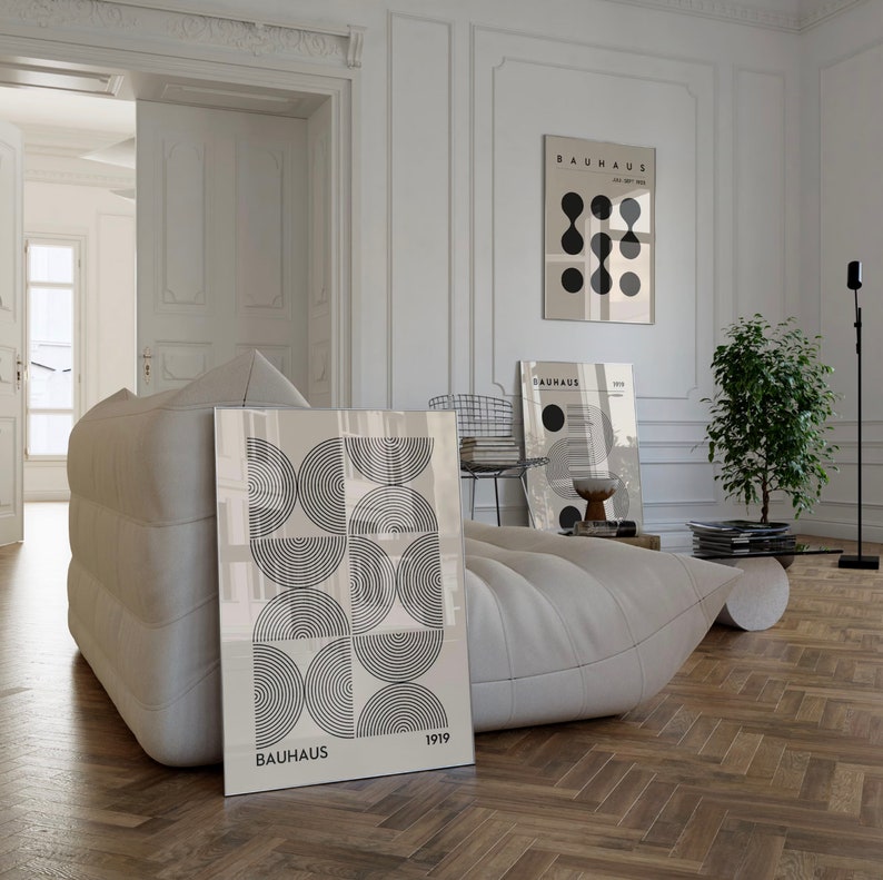 Puede incluir: Una impresi&oacute;n geom&eacute;trica en blanco y negro con el texto "BAUHAUS 1919" sobre un fondo blanco. La impresi&oacute;n est&aacute; enmarcada y colgada en una pared blanca en una sala de estar moderna.