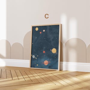 May include: A framed print of a dark blue night sky with stars and planets in various colours, including yellow, orange, and red. The print is in a light wood frame.