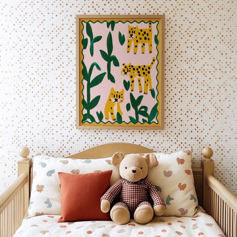 May include: A framed illustration of three leopards in a jungle setting. The leopards are depicted in a stylized, cartoon-like manner. The frame is a simple, gold-colored frame. The illustration is hanging on a wall with a white and gold patterned wallpaper. A plush teddy bear is sitting on a bed with a white and brown patterned duvet cover. The bed is made of wood and has a headboard and footboard.