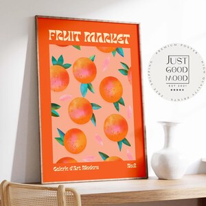 Könnte beinhalten: Orange gerahmter Kunstdruck mit einem sich wiederholenden Muster aus Orangen mit grünen Blättern und rosa Akzenten auf pfirsichfarbenem Hintergrund. Die Worte "FRUIT MARKET" stehen oben und "Galerie d'Art Modern" unten.