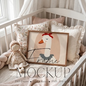 May include: A rectangular wooden frame containing a print of a white goose wearing a red bow and a grey ruffled collar, positioned next to a small doll in a floral dress. The image includes the text Frame MOCKUP PSD Frame 11x14 Ratio PSD, JPG & PNG.
