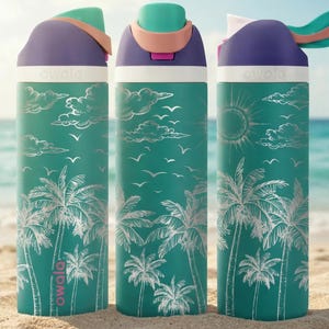 Three colorful water bottles with tropical palm tree designs are placed on a sandy beach, with the ocean visible in the background.
