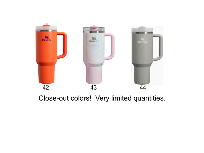 three different colored Stanley tumblers, each with a unique color: orange, pink, and gray.