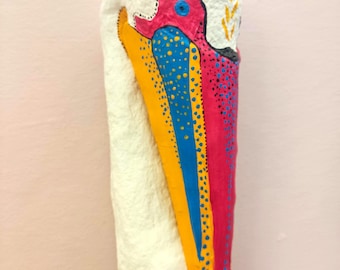 Può includere: Scultura astratta di una testa e di un becco di uccello. Il becco è dipinto in vivaci tonalità di giallo, blu e rosa, con un corpo bianco strutturato. L'opera presenta un occhio blu e motivi a pois, creando un effetto visivo sorprendente.