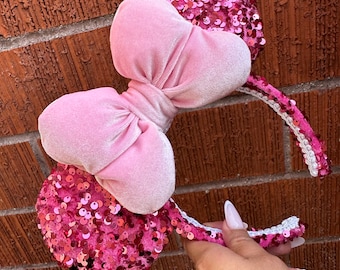 Peut inclure: Bandeau d'oreilles Minnie Mouse en sequins roses avec un grand nœud en velours rose.