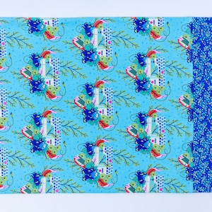 May include: A blue fabric with a repeating pattern of a sewing machine surrounded by flowers and leaves. The fabric has a blue and white polka dot border.
