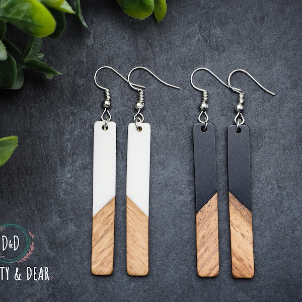 Op de afbeelding: Een paar houten oorbellen met een geometrisch ontwerp in zwart en wit. De oorbellen zijn gemaakt van hout en hebben een zilveren haak.