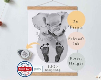 Puede incluir: Una ilustración en blanco y negro de un elefante con una huella de pie de bebé en su vientre. La ilustración está en un póster con un marco de madera. El póster también incluye el nombre "LEO" y la fecha "10.03.2024". El póster está colgado en una pared blanca con un cordero de peluche blanco y un juguete arcoíris en un estante debajo.