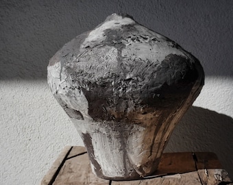 May include: A large, gray and black ceramic vase with a textured surface. The vase has a rounded, bulbous shape and a wide opening at the top.