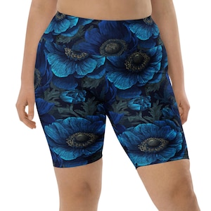 Può includere: Pantaloncini da ciclista con stampa floreale blu. I pantaloncini presentano uno sfondo blu scuro ornato da un motivo di grandi fiori blu stilizzati. Questi pantaloncini aderenti al ginocchio sono adatti per l'esercizio fisico o per l'uso quotidiano.