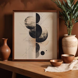 May include: A framed art print featuring a geometric design of overlapping circles in shades of black and gray, with intersecting lines and dots. The artwork is displayed on a wooden table, alongside decorative vases and bowls.