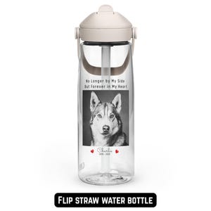 May include: Clear flip straw water bottle with a cream-colored lid and handle. The bottle features a black and white image of a dog with the text "No Longer by My Side But Forever in My Heart" and the name "Charlie" with dates.