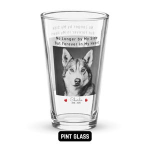 May include: Clear pint glass featuring a black and white image of a dog. The glass has the text "No Longer by My Side But Forever in My Heart" and the name "Charlie" with dates 2016-2026. The words "PINT GLASS" are at the bottom.
