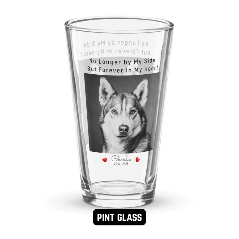 May include: Clear pint glass featuring a black and white image of a dog. The glass has the text "No Longer by My Side But Forever in My Heart" and the name "Charlie" with dates 2016-2026. The words "PINT GLASS" are at the bottom.