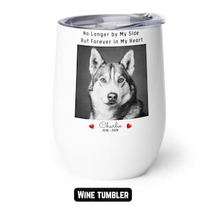 May include: White wine tumbler with a black and white image of a dog. The tumbler has the text "No Longer by My Side But Forever in My Heart" and the name "Charlie" with the years 2016-2026.