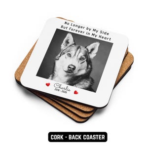May include: A stack of square cork coasters. The top coaster has a black and white photo of a dog with the text "No Longer by My Side But Forever in My Heart". Below the photo is the name "Charlie" and the years "2016-2026".