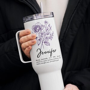 May include: White tumbler with a handle, featuring a purple floral design and the name "Jennifer" in script. Text below reads "Blooming beautifully since 1994..." Includes a clear lid and a straw.