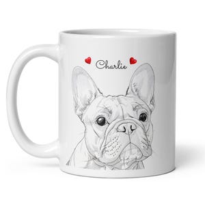 May include: White ceramic mug featuring a detailed sketch of a French Bulldog's face. The name "Charlie" is written above the dog's head, flanked by two red hearts. The mug has a curved handle.
