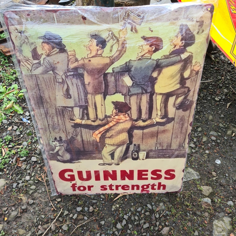 May include: Vintage metal sign advertising Guinness beer. The sign features a cartoon illustration of five men cheering, with the text "GUINNESS for strength" at the bottom.