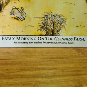 K&ouml;nnte beinhalten: Eine Vintage-Illustration eines Gerstenfeldes mit einem Hasen, der hindurchl&auml;uft. Der Text lautet "Early Morning on the Guinness Farm. An interesting new machine for harvesting our choice barley."