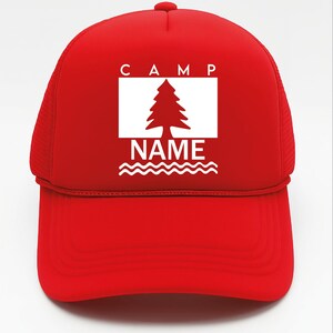 May include: A red trucker hat with a white rectangular graphic featuring a tree and the words "CAMP" and "NAME". The hat has a curved peak and mesh back.