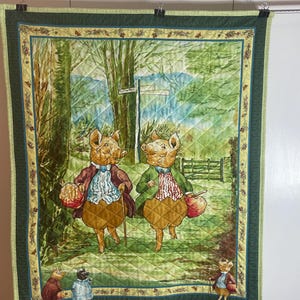 May include: A quilted wall hanging with a charming illustration of pig characters in a countryside scene. The pigs wear coats and carry bags. The quilt has a green border and a diamond pattern. The signpost reads "Down the Hills".
