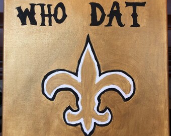 May include: Square canvas art with a gold background, featuring the words "WHO DAT" in black, above a fleur-de-lis symbol. The fleur-de-lis is outlined in black and white, with a gold center. The artwork is a sports-themed item.