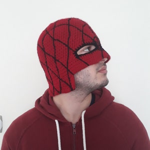 May include: A red crocheted beanie with a black spiderweb design and a matching eye mask.