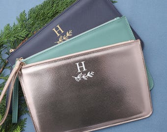 May include: Three zippered pouches in different colors: navy blue, teal green, and rose gold. Each pouch has a simple, elegant design with a single initial "H" and a small leaf sprig.