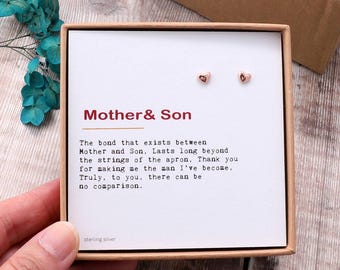 May include: A small box with a white card inside. The card has the words "Mother & Son" printed in red. The text on the card reads: "The bond that exists between Mother and Son, Lasts long beyond the strings of the apron. Thank you for making me the man I've become. Truly, to you, there can be no comparison." The card also has the words "sterling silver" printed at the bottom. There are two small rose gold heart earrings in the box.