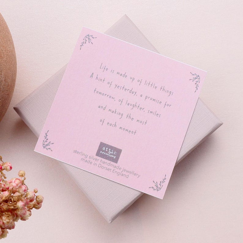 Puede incluir: Una tarjeta cuadrada de color rosa claro con texto en gris oscuro que dice: Life is made up of little things, A hint of yesterday, a promise for tomorrow, of laughter, smiles and making the most of each moment. Tiene peque&ntilde;os detalles de hojas.