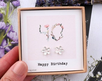 May include: A small gift box with a pink card inside that says "Happy Birthday" and features a floral design in the shape of the number 40. The box contains a pair of silver flower-shaped earrings.
