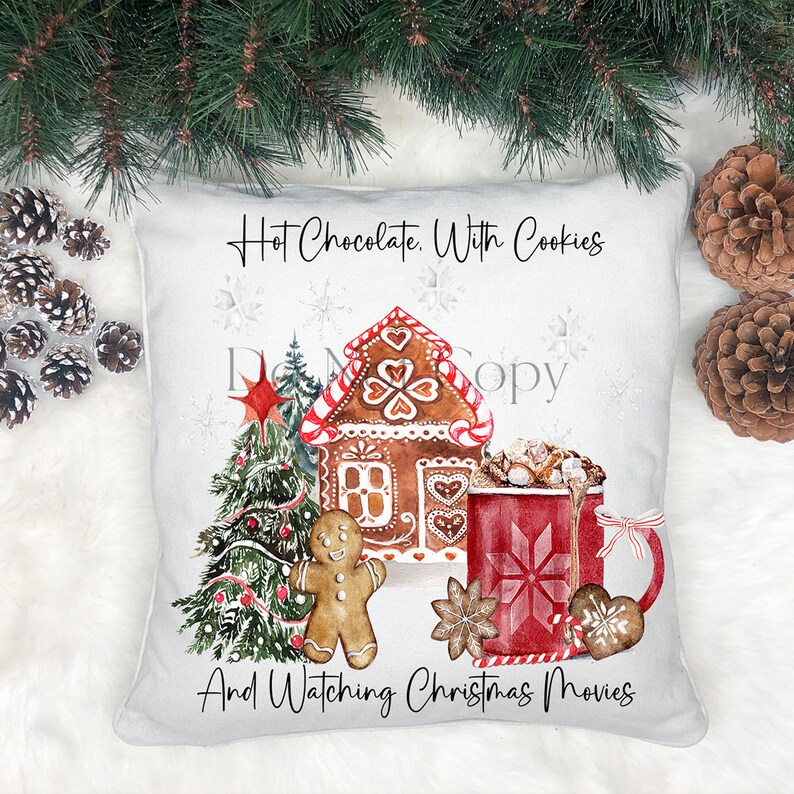 May include: A white throw pillow with a Christmas-themed design. The pillow features a gingerbread house, a Christmas tree, a gingerbread man, a mug of hot chocolate with marshmallows, and the text "Hot Chocolate. With Cookies And Watching Christmas Movies".