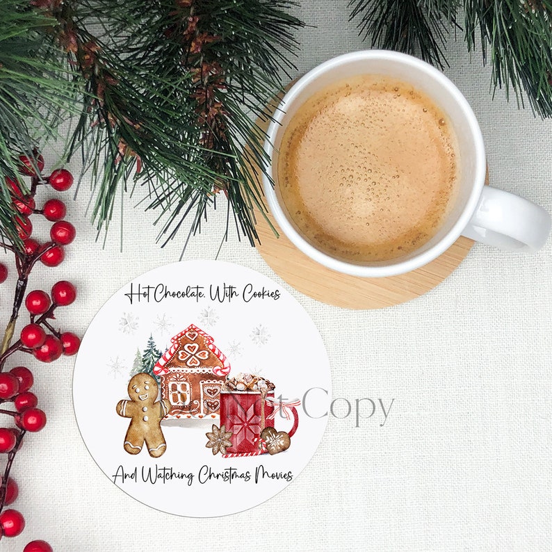 May include: White round coaster with a gingerbread house, gingerbread man, and a red mug with hot chocolate. The text on the coaster reads "Hot Chocolate With Cookies And Watching Christmas Movies".