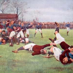 May include: A vintage illustration of a rugby match in progress. Players in maroon and white uniforms are tackling each other on a green field. The players are wearing short pants and long socks. There is a goal post in the background.