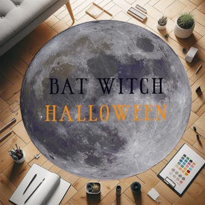 Puede incluir: Una alfombra redonda con una imagen detallada de la luna con las palabras "BAT WITCH HALLOWEEN" en negro y naranja. La alfombra está sobre un suelo de madera, rodeada de material de oficina y pequeñas plantas.
