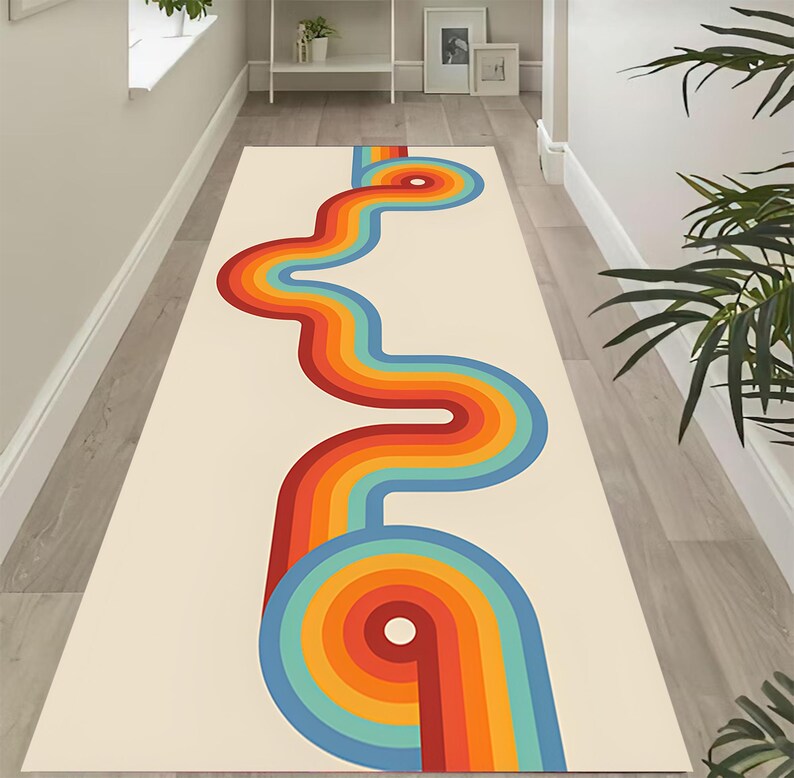May include: A cream-colored runner rug with a retro design. The rug features a vibrant, winding pattern in shades of red, orange, yellow, blue, and teal. The design resembles a stylized road or river, adding a pop of color to any hallway or entryway.