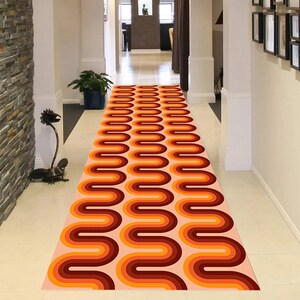 Op de afbeelding: Een lang, smal looptapijt met een retro, geometrisch patroon in tinten oranje, bruin en perzik. Het tapijt heeft een golvend, gebogen ontwerp dat lijkt op een reeks bogen.