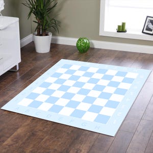 Puede incluir: Una alfombra de tablero de ajedrez a cuadros azul claro y blanco. La alfombra tiene un borde azul claro con letras y números a lo largo de los bordes. El patrón de cuadros está formado por cuadrados alternos azul claro y blancos. La alfombra está sobre un suelo de madera.
