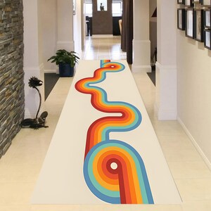 May include: A long, rectangular rug with a retro design. The rug features a cream-colored background with a vibrant, winding pattern in shades of red, orange, yellow, and blue. The design is reminiscent of the 1970s era, adding a pop of color to a hallway.