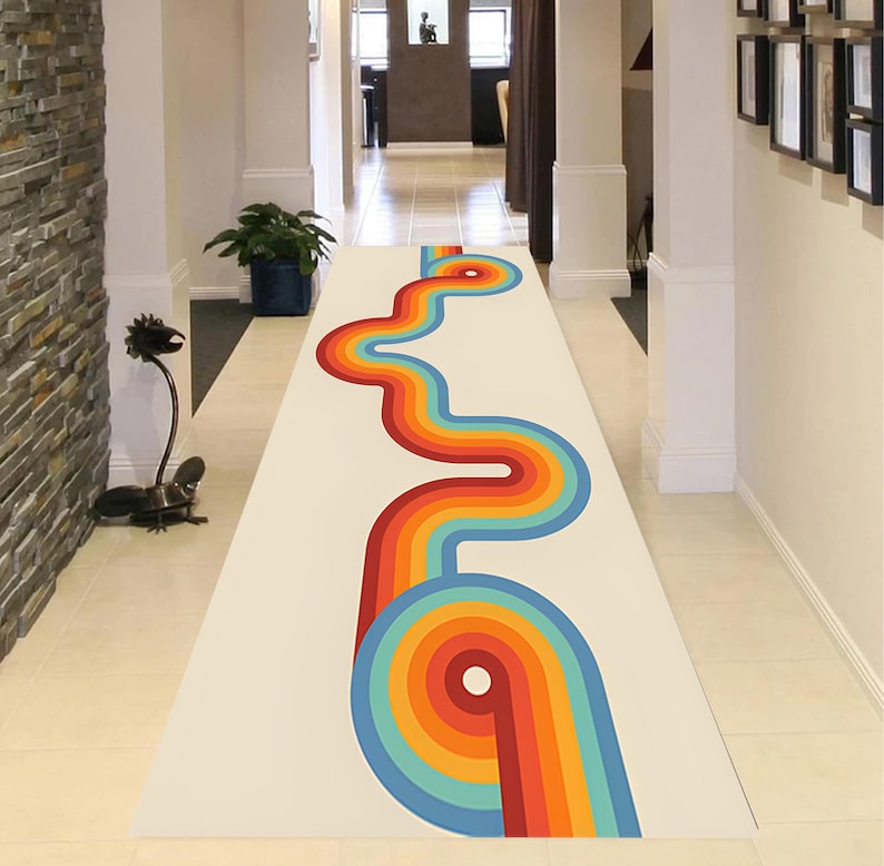 May include: A long, rectangular rug with a retro design. The rug features a cream-colored background with a vibrant, winding pattern in shades of red, orange, yellow, and blue. The design is reminiscent of the 1970s era, adding a pop of color to a hallway.