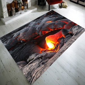 May include: A close-up of a rug featuring a realistic image of lava rock and glowing orange lava. The rug is ideal for adding a dramatic and unique touch to any room.