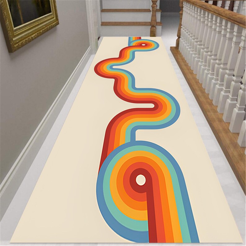 May include: A cream-colored runner rug with a retro design. The rug features a vibrant, winding pattern of rainbow-colored stripes, including red, orange, yellow, green, and blue. The design is centered on the rug, creating a bold, eye-catching statement.