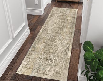 May include: A long, rectangular runner rug featuring a distressed, faded pattern in shades of beige, cream, and charcoal gray. The rug displays an intricate, traditional-style floral and medallion motif across its surface, laid on dark wood flooring.