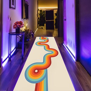 May include: A hallway runner rug with a retro design. The rug features a cream background with a colorful, wavy pattern in shades of red, orange, yellow, blue, and green. The rug is rectangular and placed in a hallway.