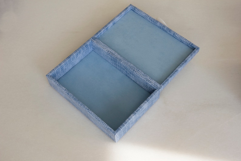 May include: A light blue jewellery box with two compartments. The box has a textured, crocodile-embossed design.