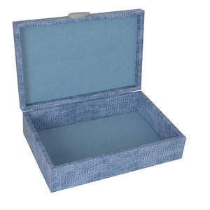 May include: A light blue box with a crocodile-embossed pattern. The box is open and the inside is lined with a light blue fabric.