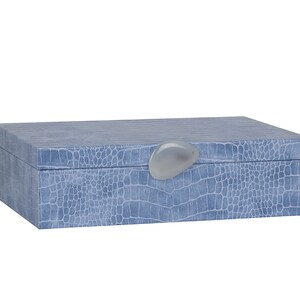 May include: A light blue rectangular box with a crocodile-embossed pattern and a white oval-shaped knob on the lid.